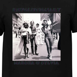 T-shirt noir avec photo de trois personnes marchant en ville et textes “Revolutionary” et “Marsha & Sylvia”.