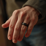 Bague en tungstène noir avec bande galaxie discrète, portée à l’annulaire sur une main, montrant un rendu sobre, élégant et quotidien.