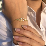 Bracelet lesbien double Vénus doré porté au poignet, bijou fin symbolisant l’amour entre femmes