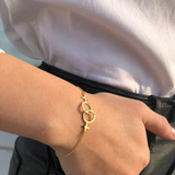Bracelet double Vénus lesbien en finition dorée sur poignet féminin, symbole discret d’identité lesbienne