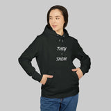 Personne portant le sweat à capuche non binaire THEY THEM, mains dans la poche kangourou