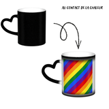 Mug en céramique avec poignée en forme de cœur. À froid, l’extérieur est uniformément coloré (noir, bleu ou rouge) avec de petits points blancs. Au contact de la chaleur, le centre devient blanc et révèle un grand rectangle composé de bandes diagonales arc-en-ciel : rouge, orange, jaune, vert, bleu et violet, orientées du coin supérieur gauche vers le coin inférieur droit. Le contraste reste visible entre la zone éclaircie et la couleur d’origine du mug.