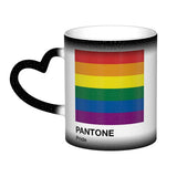 Mug en céramique avec poignée en forme de cœur. À froid, la surface extérieure est uniformément colorée (noir, bleu ou rouge) avec de petits points blancs dispersés. Au contact de la chaleur, le centre du mug devient blanc et révèle un carré composé de six bandes horizontales : rouge en haut, puis orange, jaune, vert, bleu et violet. Sous le carré figurent les mots « PANTONE » puis « Pride ». Le contraste entre la zone blanche révélée et la couleur d’origine reste visible autour du mug.
