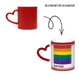 Mug en céramique avec poignée en forme de cœur. À froid, la surface extérieure est uniformément colorée (noir, bleu ou rouge) avec de petits points blancs dispersés. Au contact de la chaleur, le centre du mug devient blanc et révèle un carré composé de six bandes horizontales : rouge en haut, puis orange, jaune, vert, bleu et violet. Sous le carré figurent les mots « PANTONE » puis « Pride ». Le contraste entre la zone blanche révélée et la couleur d’origine reste visible autour du mug.