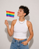 Petit drapeau Pride arc-en-ciel tenu à la main sur fond clair