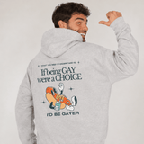 Homme portant un hoodie gris chiné avec capuche et doublure intérieure chaude. Au dos, un visuel rétro affiche la phrase “If being GAY were a CHOICE I’d be GAYER” en grandes lettres foncées. Une illustration de hot-dog cartoon avec chaussures et boisson apparaît sous le texte, entourée de petites étoiles graphiques. Le mannequin sourit et pointe son pouce vers le design imprimé dans son dos.