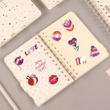 Image montrant plusieurs stickers lesbien collés sur un ordinateur portable et un carnet, illustrant leur usage décoratif au quotidien.