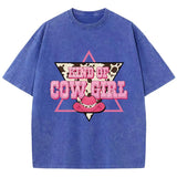 T-shirt oversize aux couleurs délavées avec imprimé “Kind of Cowgirl”, triangle rose, motif peau de vache et chapeau cowgirl rose, style western queer.