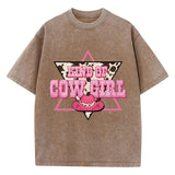 T-shirt oversize aux couleurs délavées avec imprimé “Kind of Cowgirl”, triangle rose, motif peau de vache et chapeau cowgirl rose, style western queer.