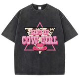 T-shirt oversize aux couleurs délavées avec imprimé “Kind of Cowgirl”, triangle rose, motif peau de vache et chapeau cowgirl rose, style western queer.