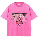 T-shirt oversize aux couleurs délavées avec imprimé “Kind of Cowgirl”, triangle rose, motif peau de vache et chapeau cowgirl rose, style western queer.