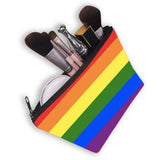 Trousse rectangulaire en tissu polyester, ornée de six bandes horizontales du drapeau arc-en-ciel : rouge en haut, puis orange, jaune, vert, bleu et violet. Une fermeture éclair noire traverse la largeur supérieure. La trousse est légèrement ouverte, laissant apparaître divers pinceaux et petits accessoires. Les couleurs sont pleines, disposées de manière régulière et reconnaissable.