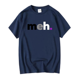 T-shirt uni avec le mot “meh.” centré sur la poitrine. La lettre “m” est noire, le “e” est gris foncé, le “h” est blanc et le point final est violet. Le vêtement est présenté à plat dans plusieurs couleurs : gris clair, anthracite et bleu marine.